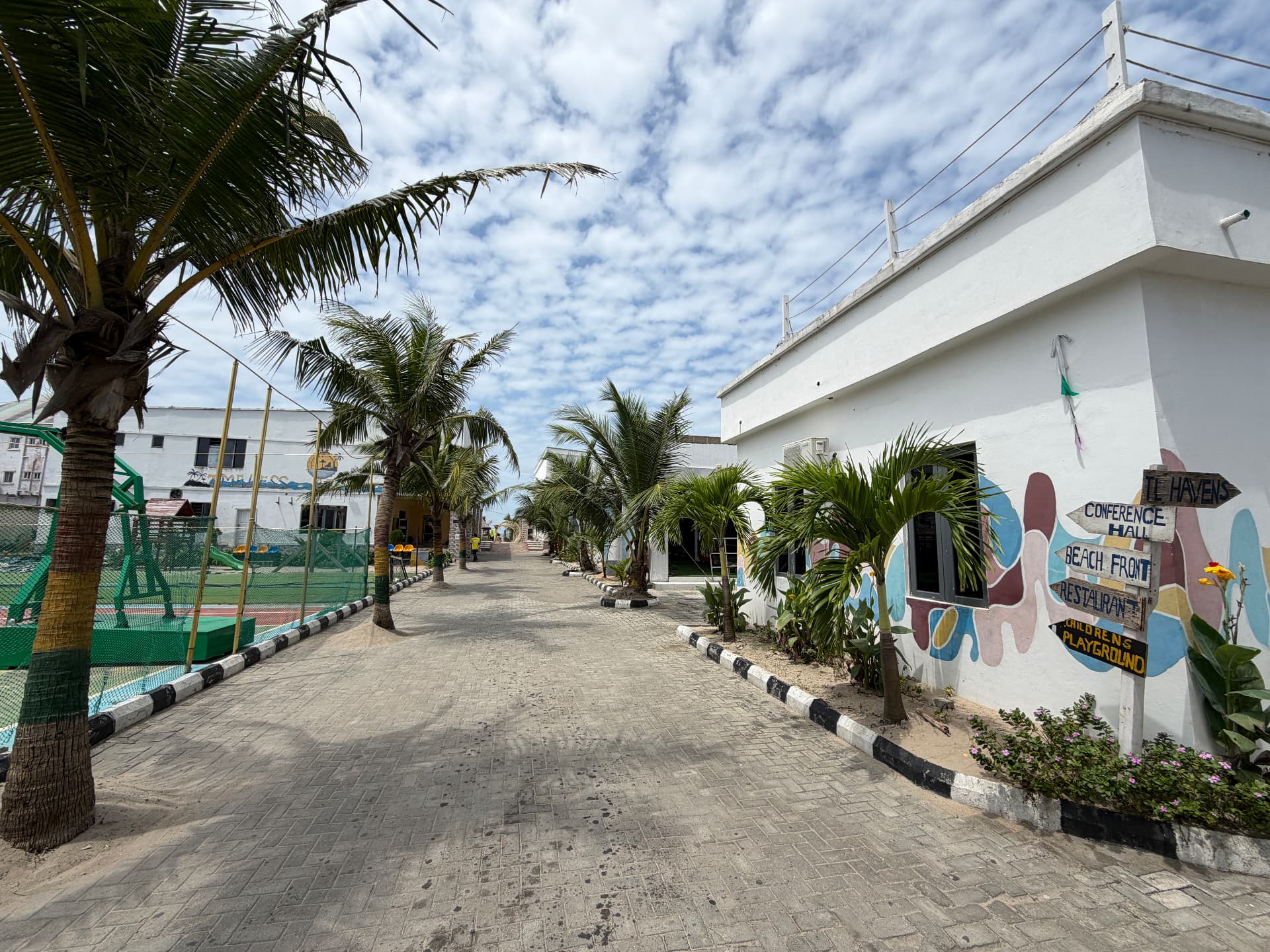 Palm-lined walkway with directional signs to the beachfront and conference hall