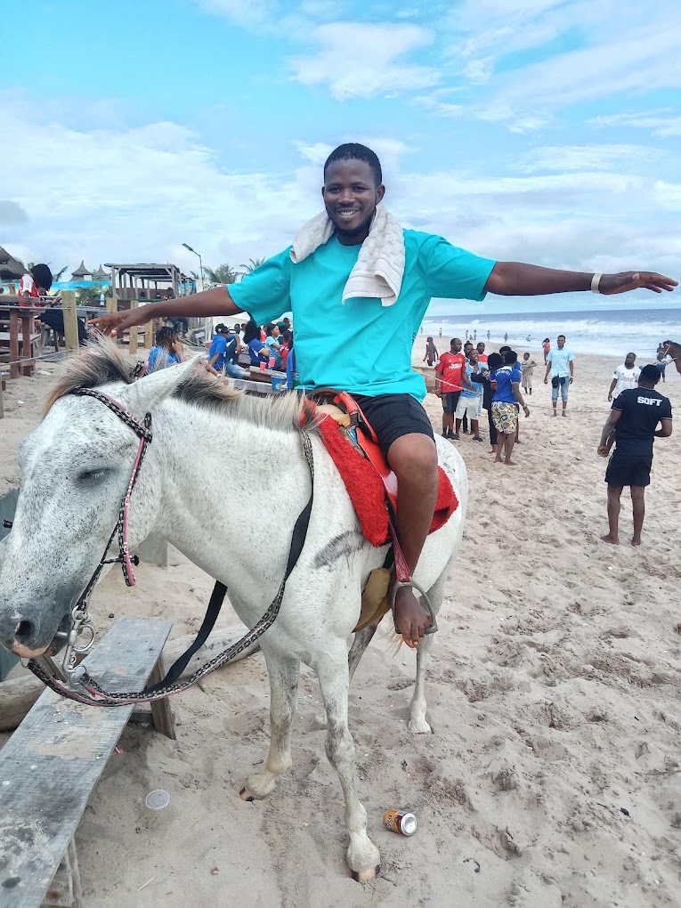 Smiling guest riding a white horse on the sand at Timeless Beach Resort