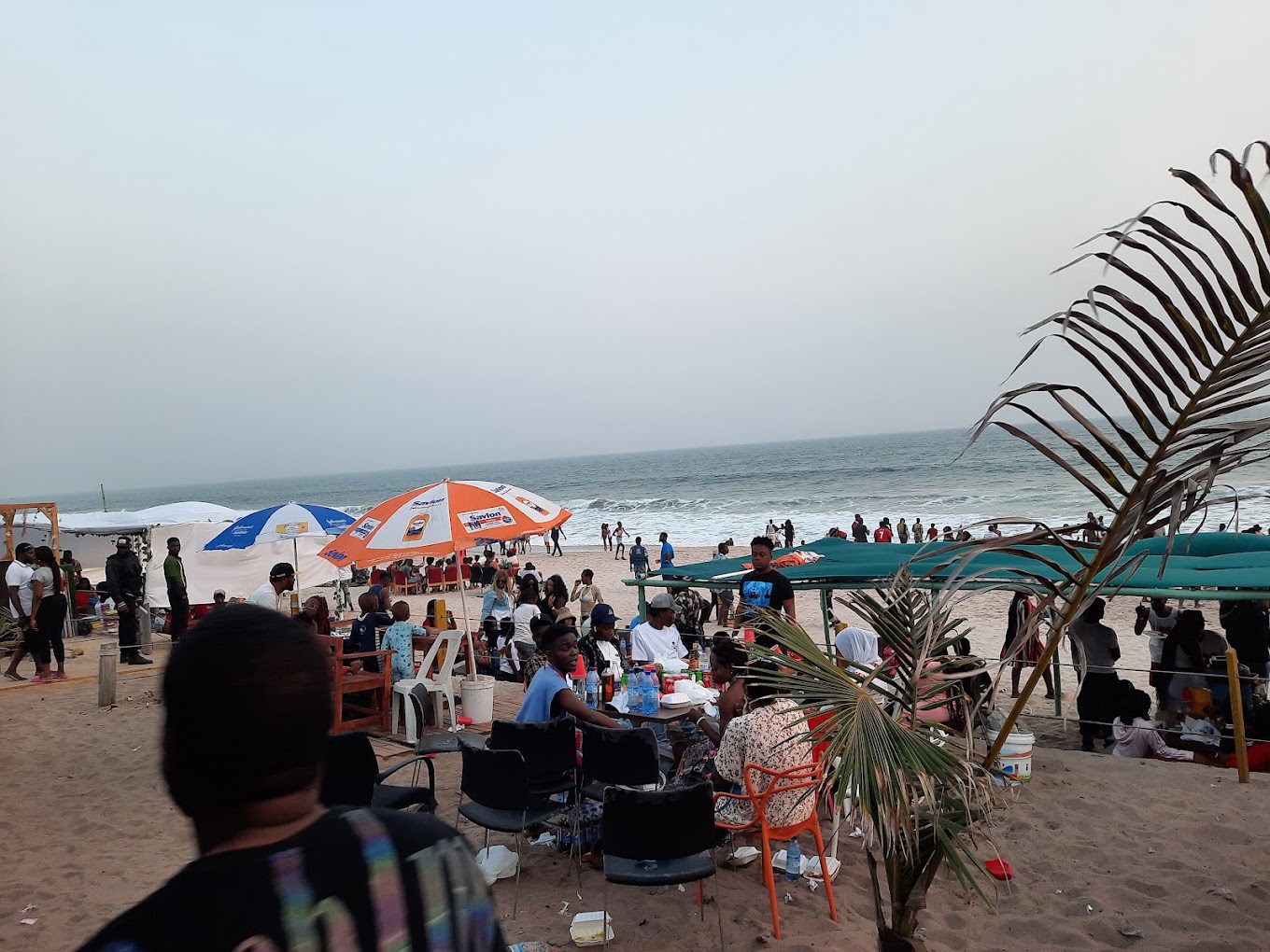 Beachgoers under parasols and shaded seating along the shoreline at the resort